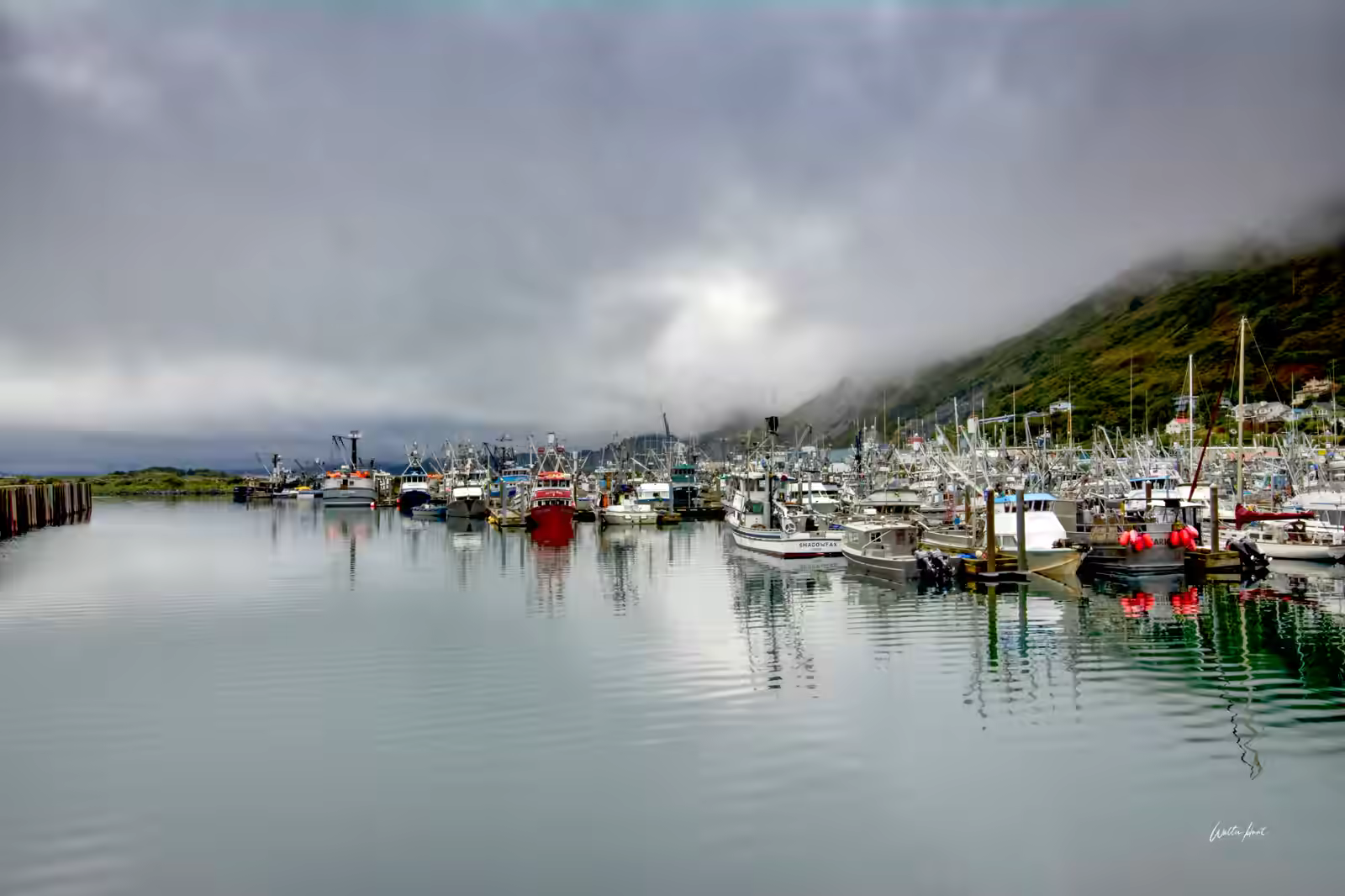 Fishing boats resting beneath fog-covered mountains in Kodiak Harbor